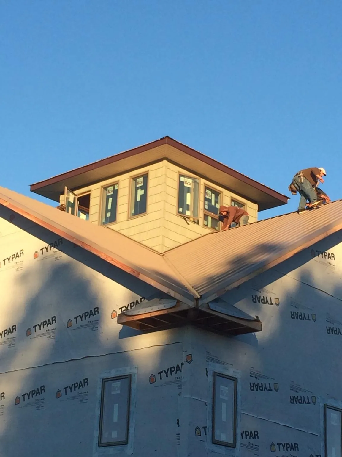 Roofers working around a rooftop cupola on a new metal roof at sunset — Roof Waterproofing in Star by Roofing Brothers